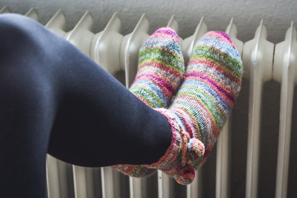 Füße in Socken lehnen gegen eine Heizung.