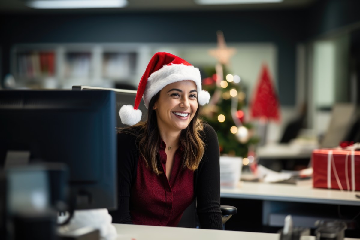 Eine Frau sitzt mit einer Nikolausmütze im Büro.