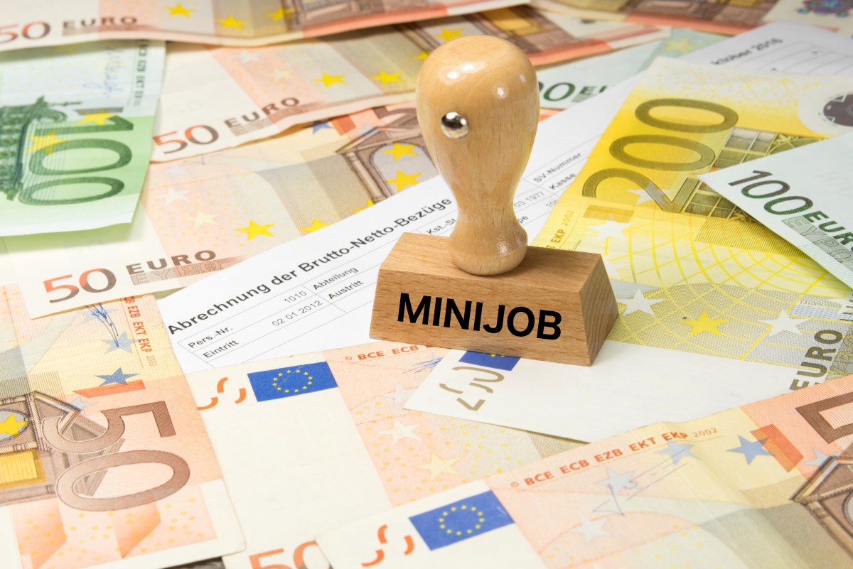 Ein Stempel mit der Aufschrift "Minijob" steht auf Geldscheinen.