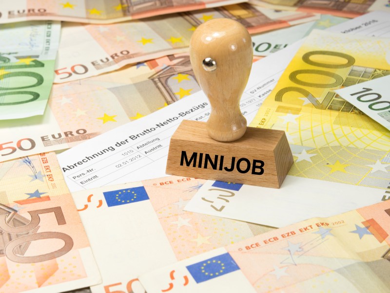 Ein Stempel mit der Aufschrift "Minijob" steht auf Geldscheinen.