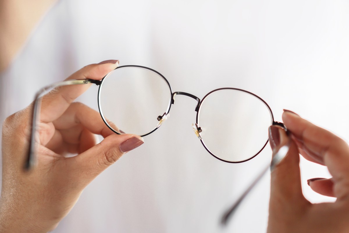 Eine Person hält eine Brille in der Hand.