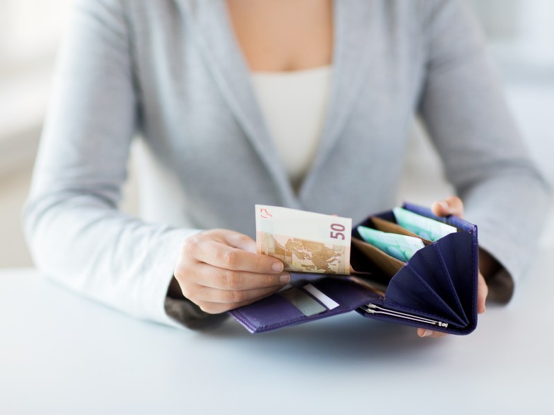 Frau zieht einen 50-Euro-Schein aus dem Portemonnaie.