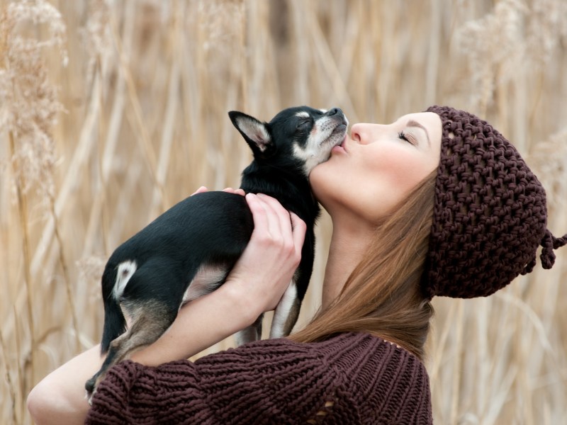 Frau küsst Hund auf Schnauze