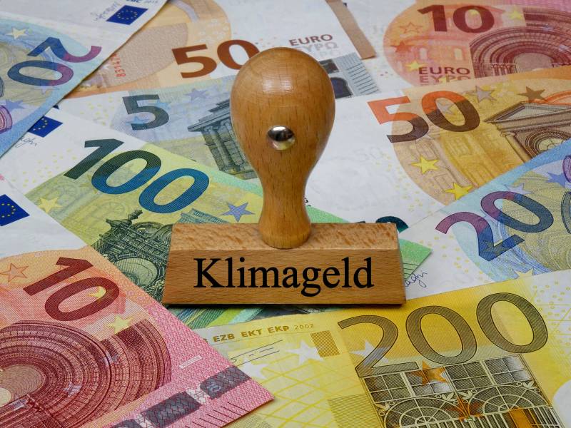 Ein Stempel mit der Aufschrift "Klimageld" liegt auch Euro-Scheinen.