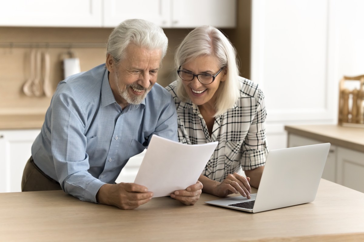 Ein Seniorenpaar schaut freudig auf ein Dokument.