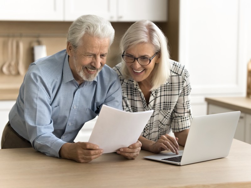 Ein Seniorenpaar schaut freudig auf ein Dokument.