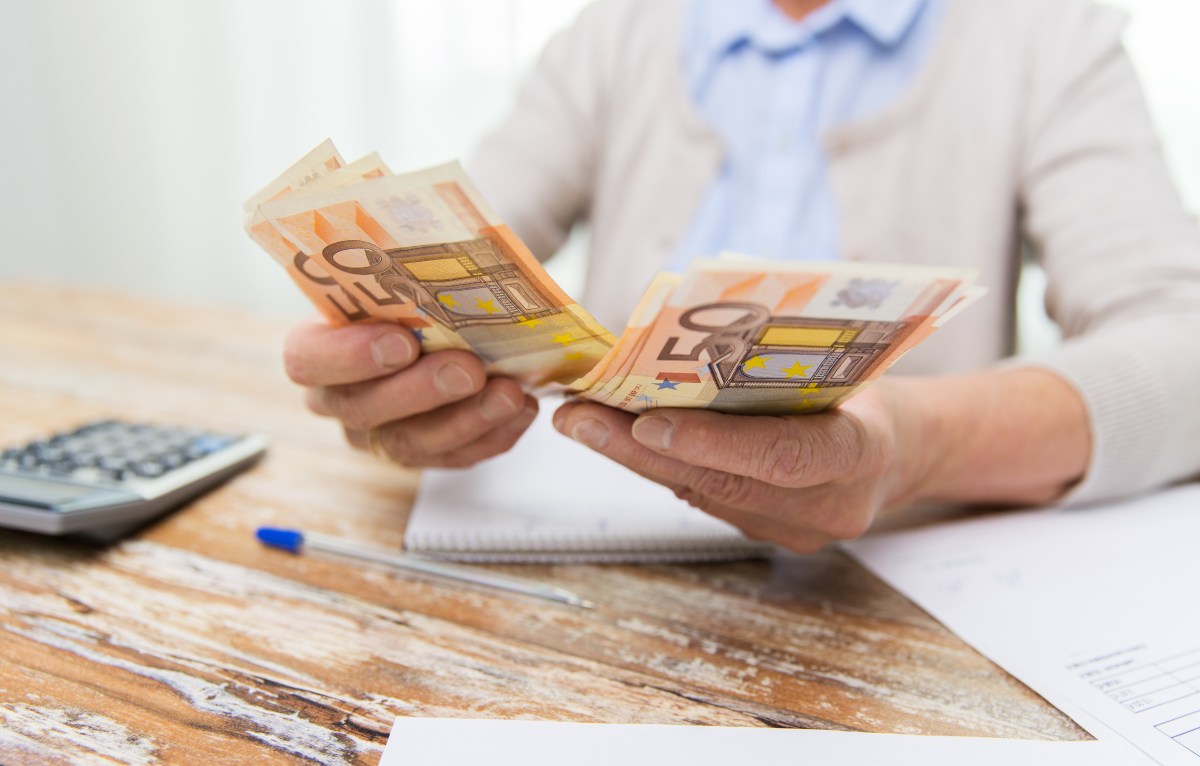 Eine älter Person hält mehrere 50-Euro-Scheine in der Hand.