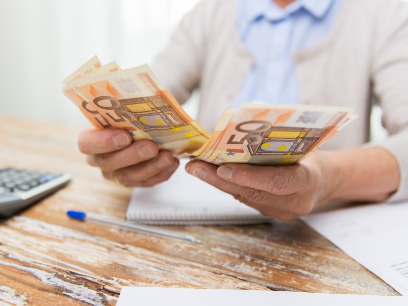 Eine älter Person hält mehrere 50-Euro-Scheine in der Hand.