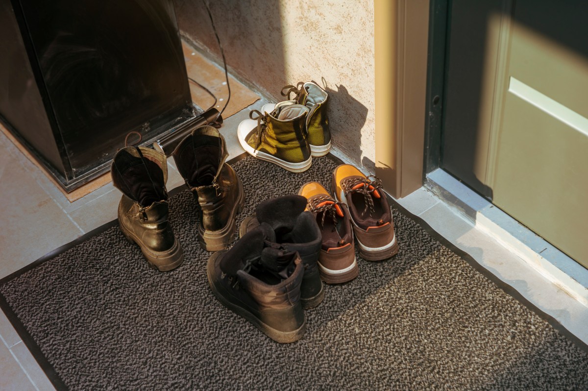 Vier Paar Schuhe stehen vor einer Haustür.