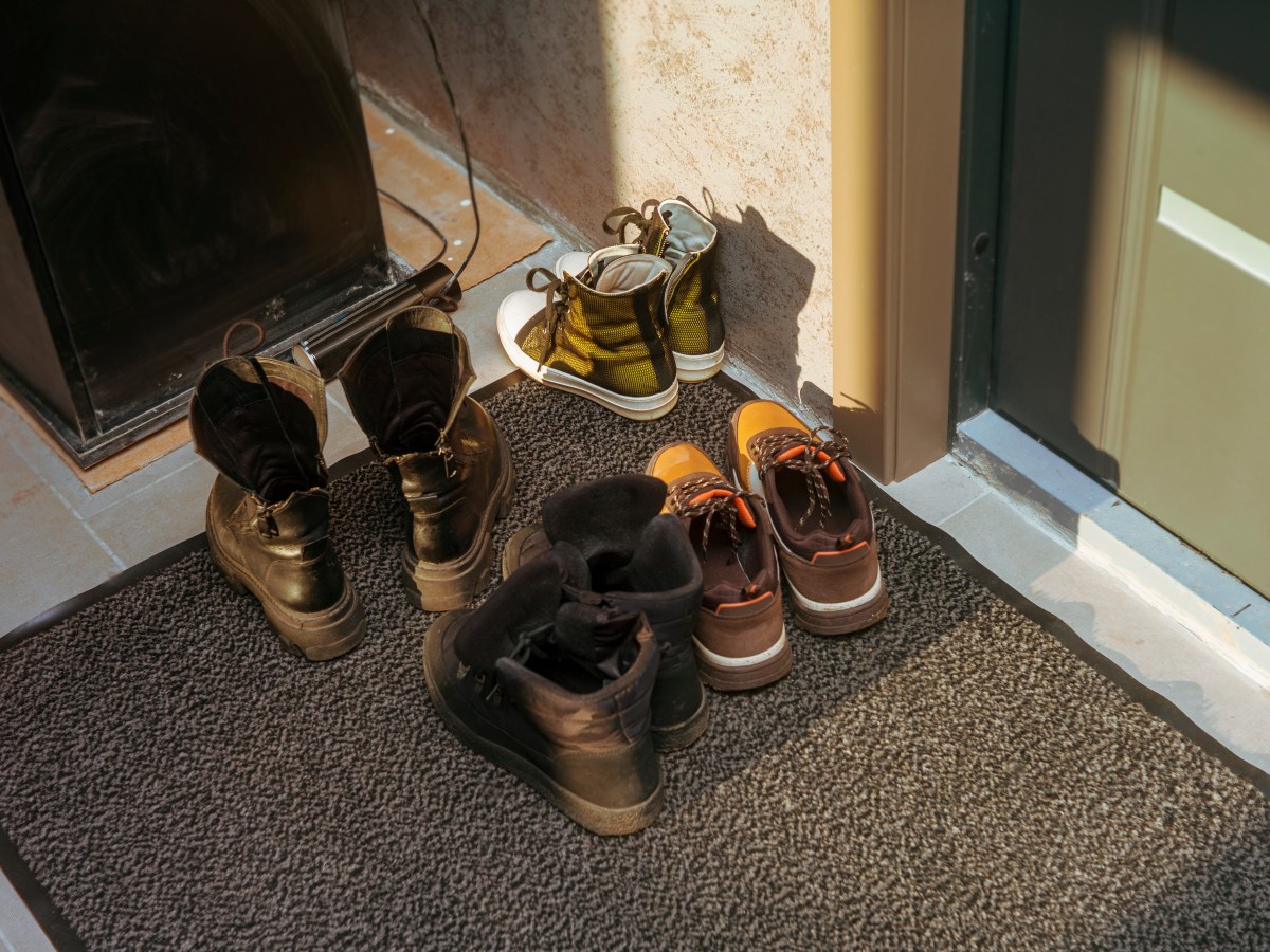 Vier Paar Schuhe stehen vor einer Haustür.