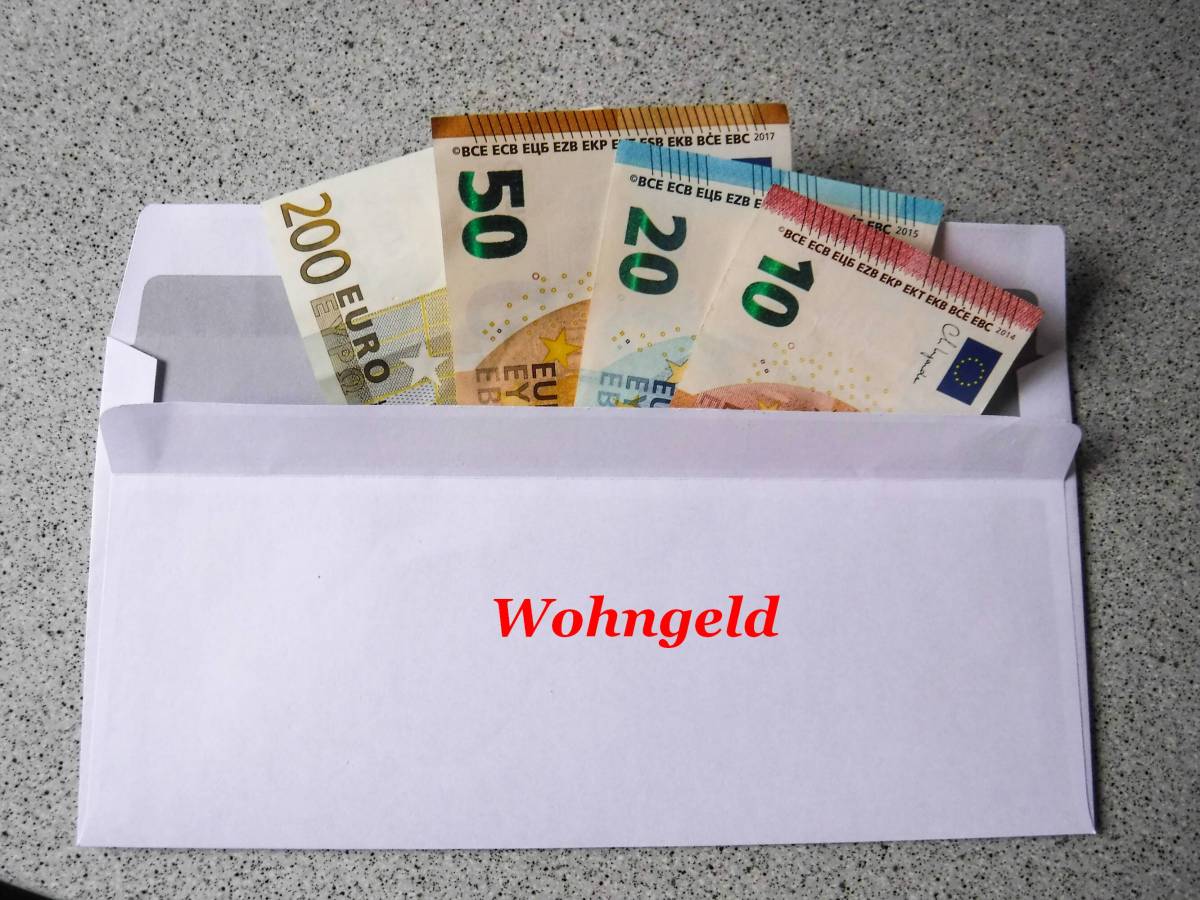 Ein Umschlag mit Geld. Auf diesem steht das Wort "Wohngeld".