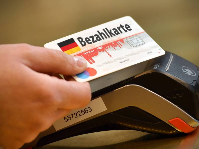 Eine Person hält eine Bezahlkarte an Kartenlesegerät.