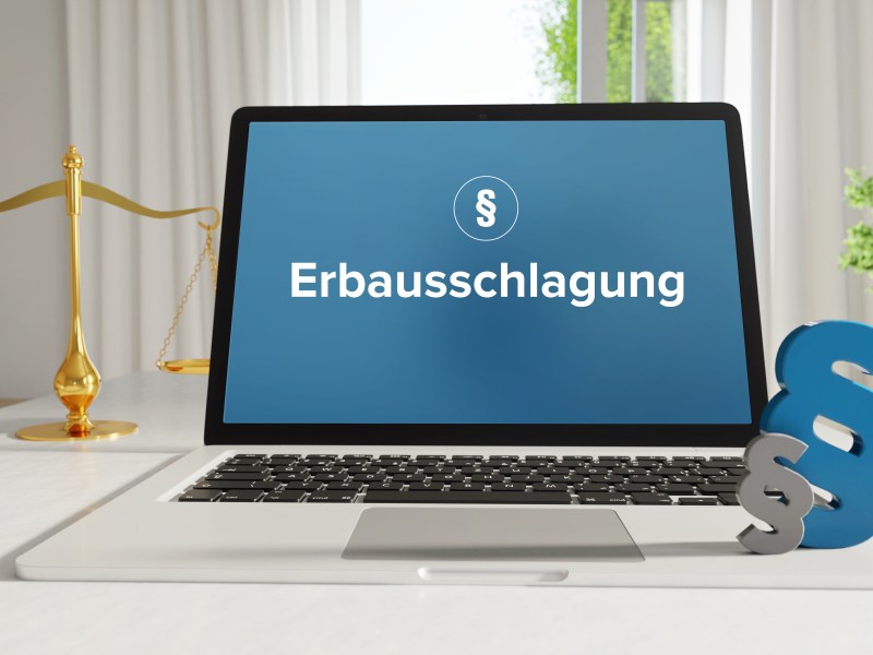 Auf einem Kaptop steht das Wort "Erbausschlagung". Daneben steht eine Gerichtswaage.