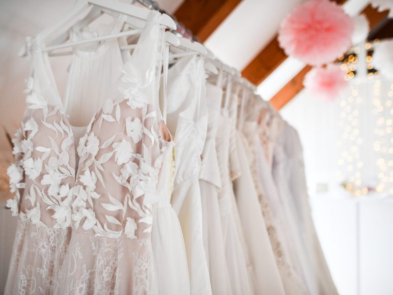 Brautkleider hängen auf einer Stange.