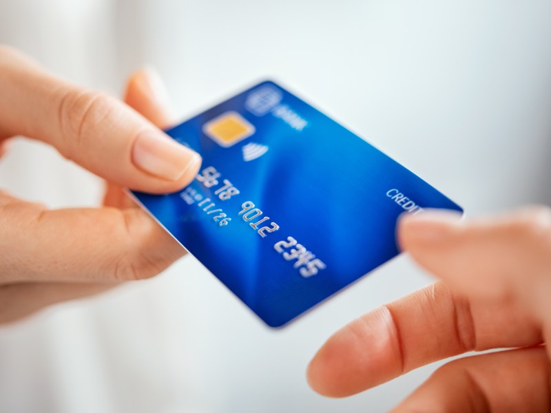 Eine Hand überreicht einer anderen Hand eine Kreditkarte.
