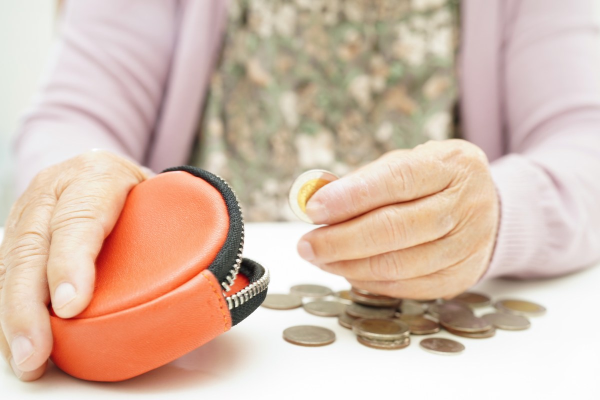 Eine alte Dame zählt die Münzen in ihrem Portemonnaie.