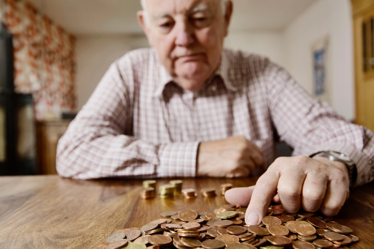 Ein Senior sitzt am Tisch und zählt Münzen.