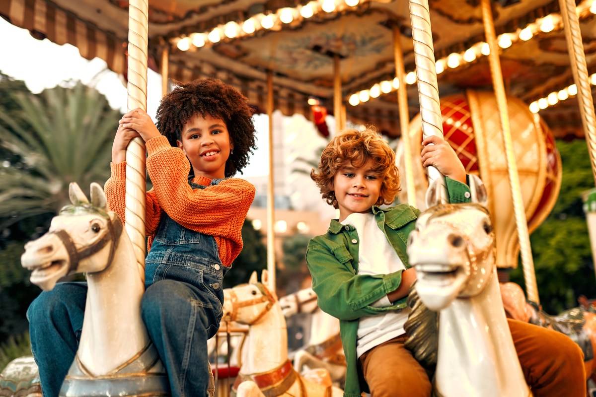 Kinder sitzen auf Karussell mit Tieren