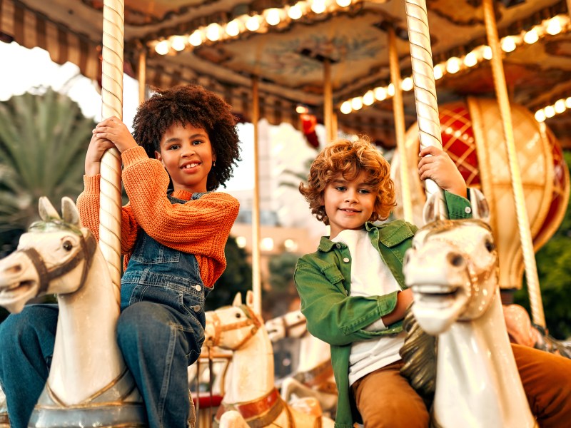 Kinder sitzen auf Karussell mit Tieren