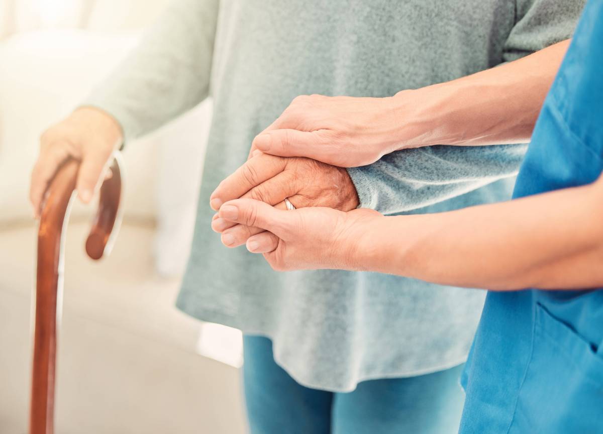 Eine ältere Person mit Gehstock wird die Hand gehalten.