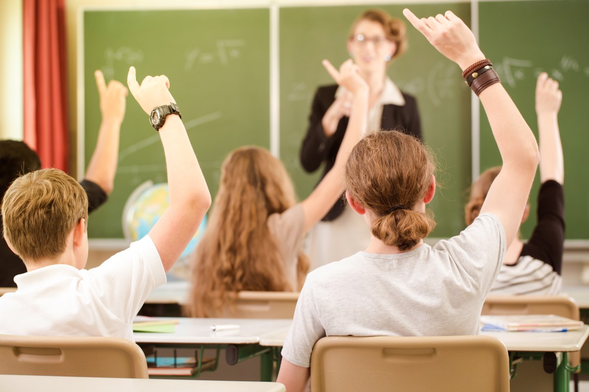 Jugendliche sitzen im Klassenzimmer und melden sich.