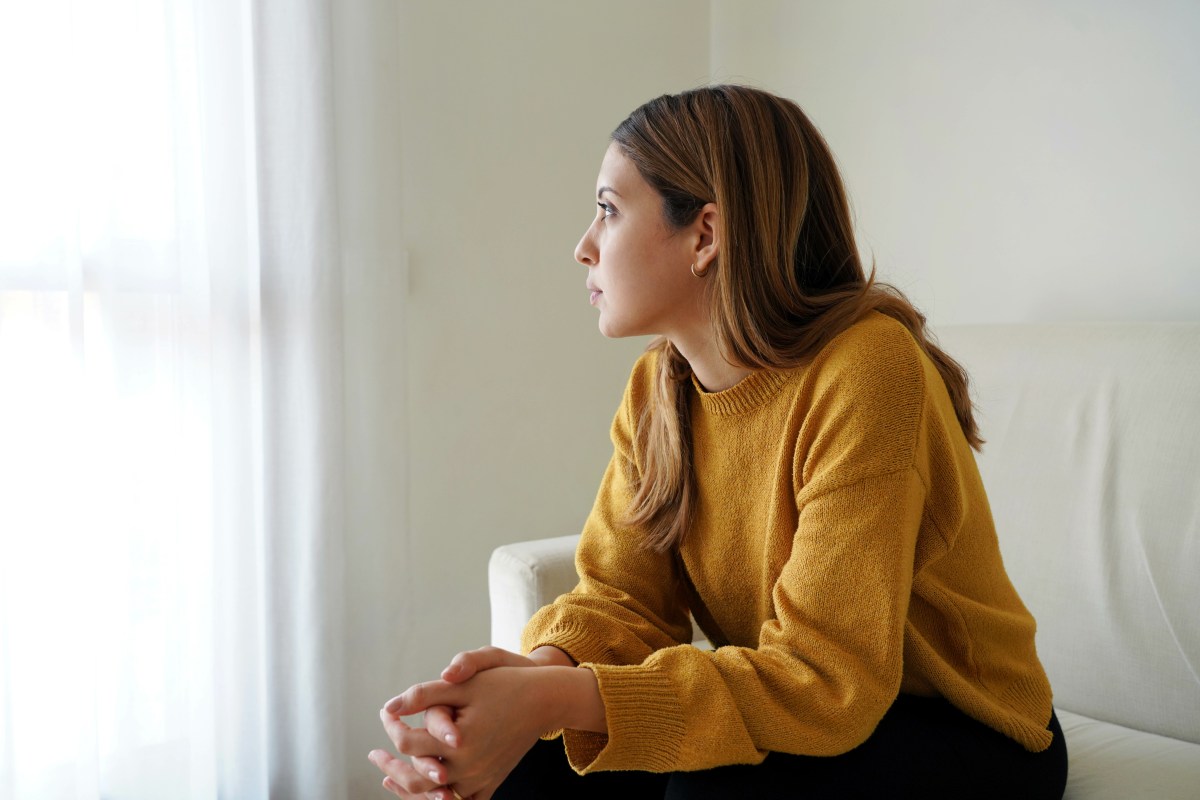 Eine junge Frau schaut traurig aus dem Fenster.