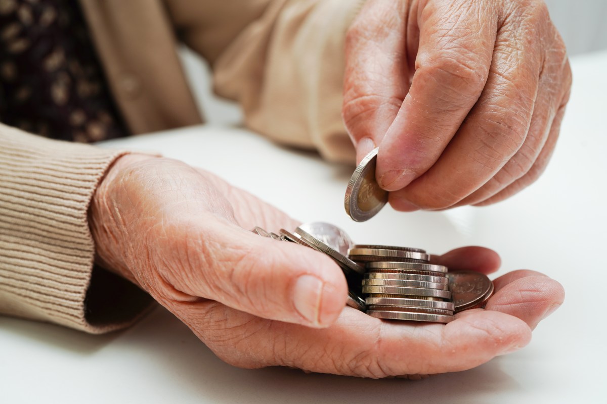 Eine ältere Dame legt Münzen in ihre Hand.