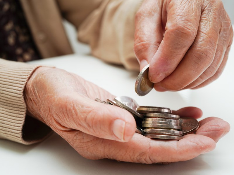 Eine ältere Dame legt Münzen in ihre Hand.
