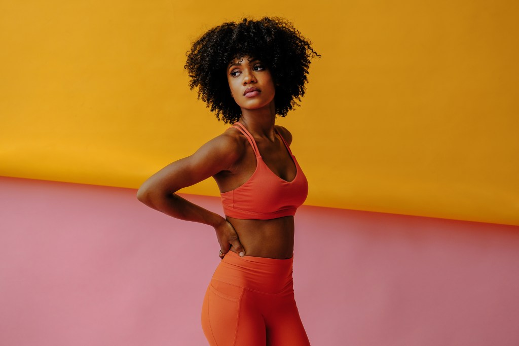 Eine Frau mit orangenem Gym Outfit.