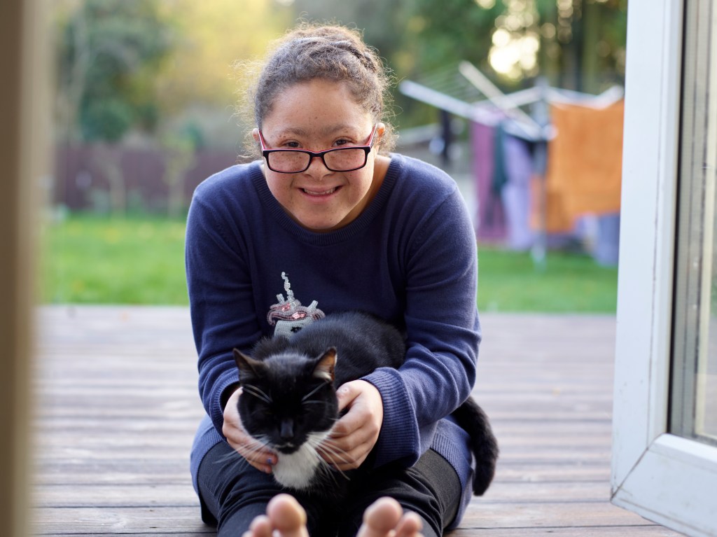 Frau mit Down Syndrom hält Katze auf dem Schoß