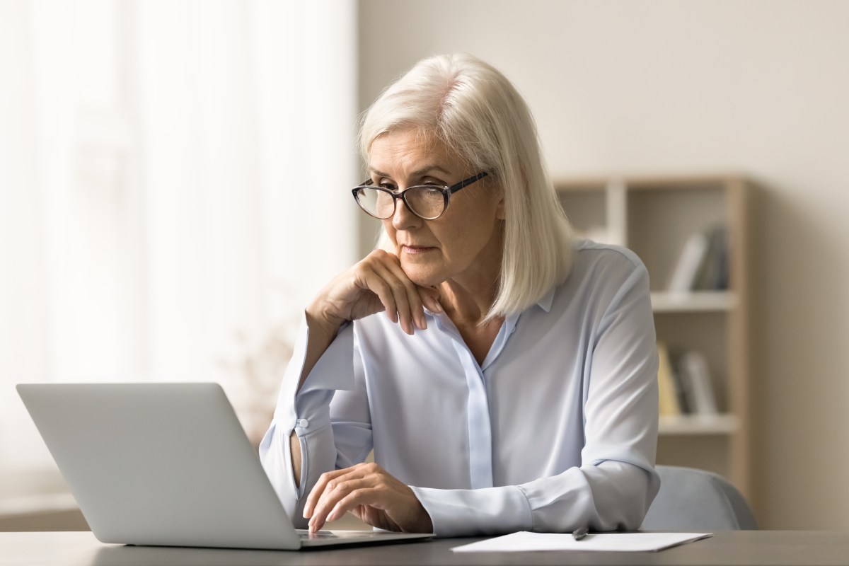 Eine ältere Dame sitzt vor dem Laptop und arbeitet.