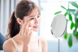 Junge Frau trÃ¤gt Sonnencreme auf ihr Gesicht auf