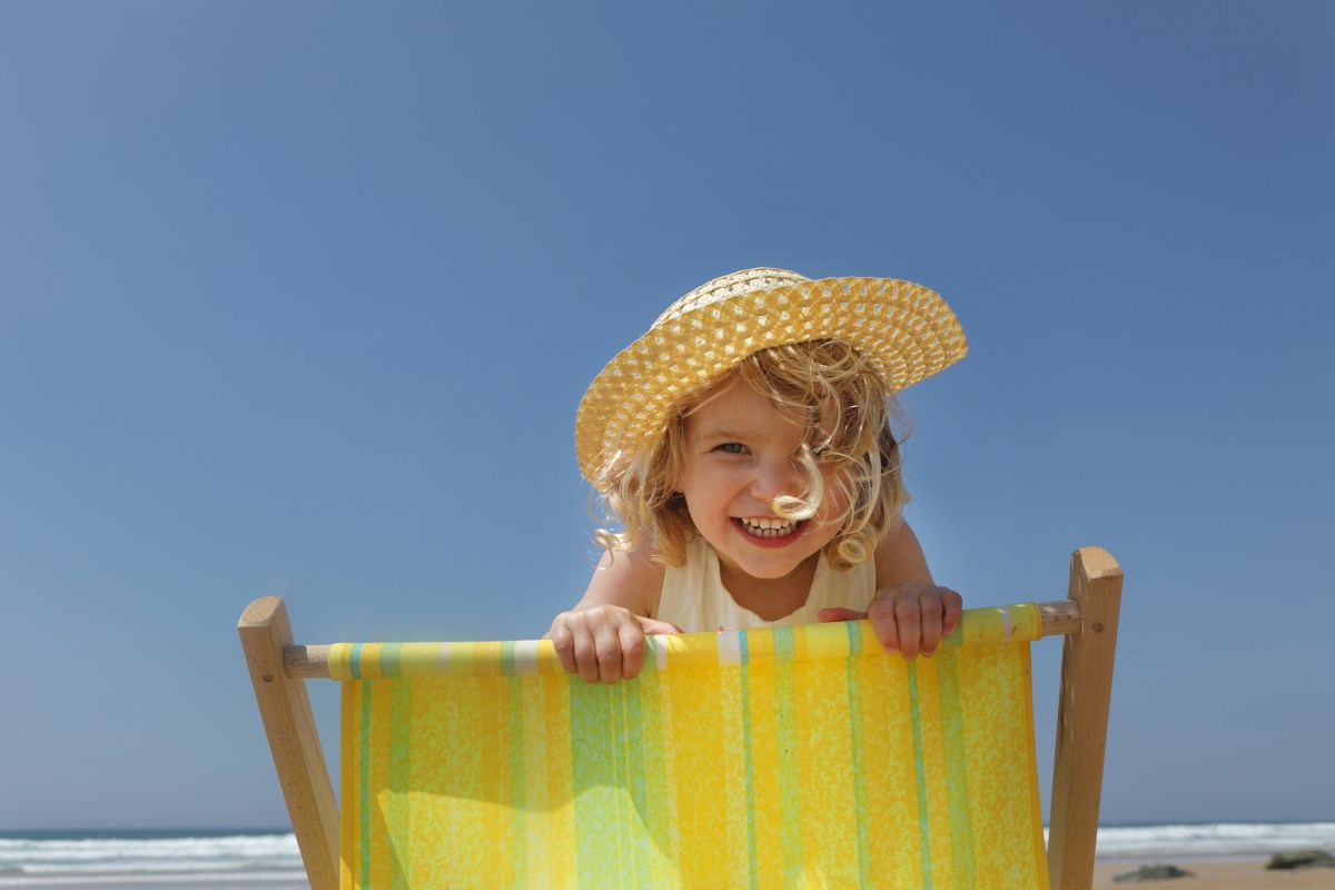 Kind mit Sonnenhut auf Strandliege in der Sonne