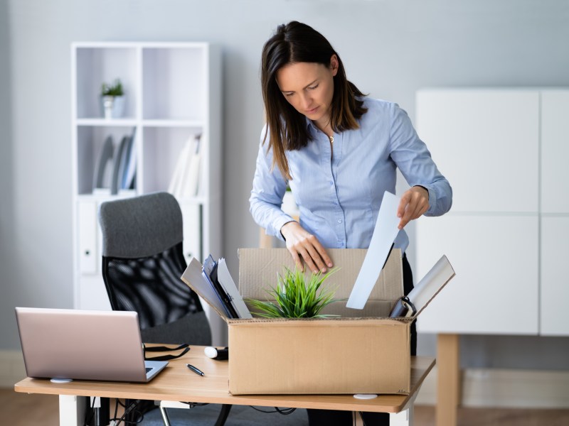 Eine Frau packt im Büro ihre Sachen in eine Kiste.