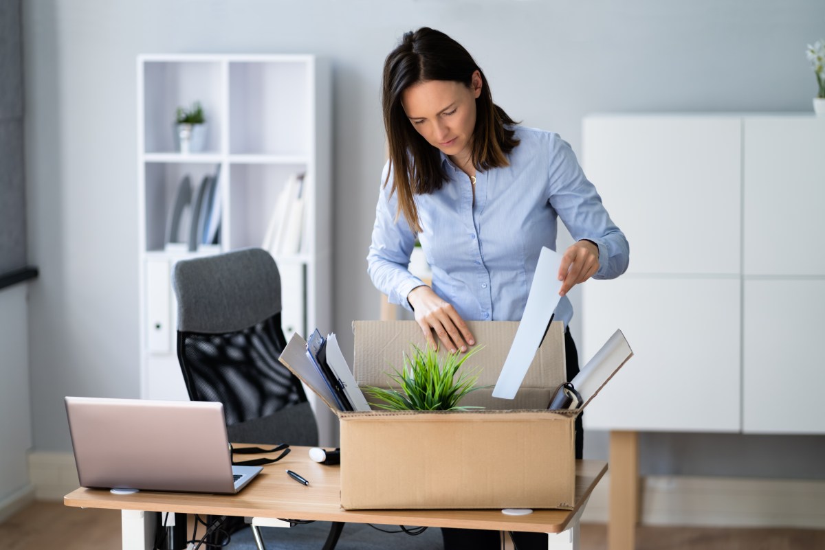 Eine Frau packt im Büro ihre Sachen in eine Kiste.