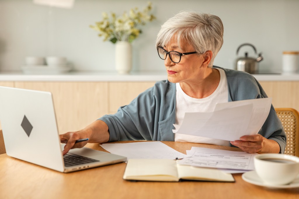 Eine Seniorin bearbeitet Dokumente und tippt auf dem Computer.