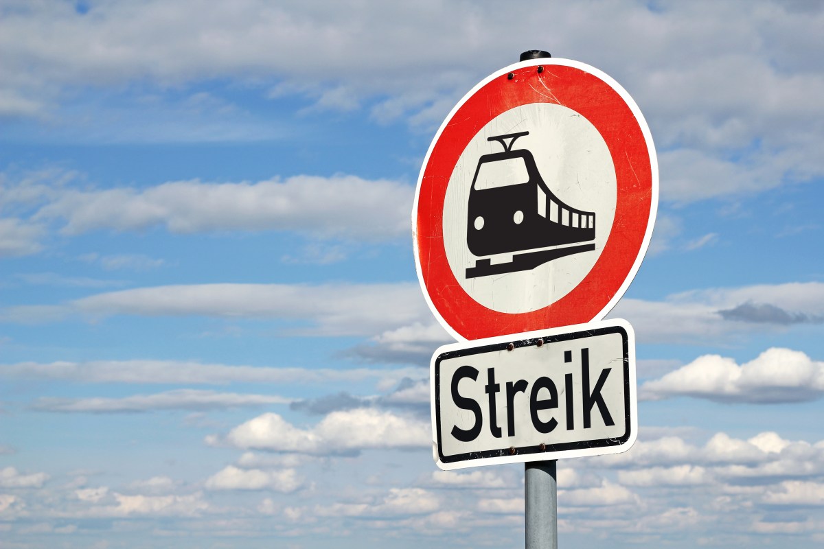 Auf einem runden Schild ist ein Zug abgebildet. Darunter steht das Wort 