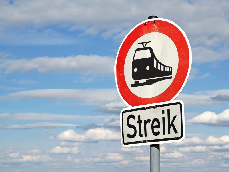 Auf einem runden Schild ist ein Zug abgebildet. Darunter steht das Wort "Streik".