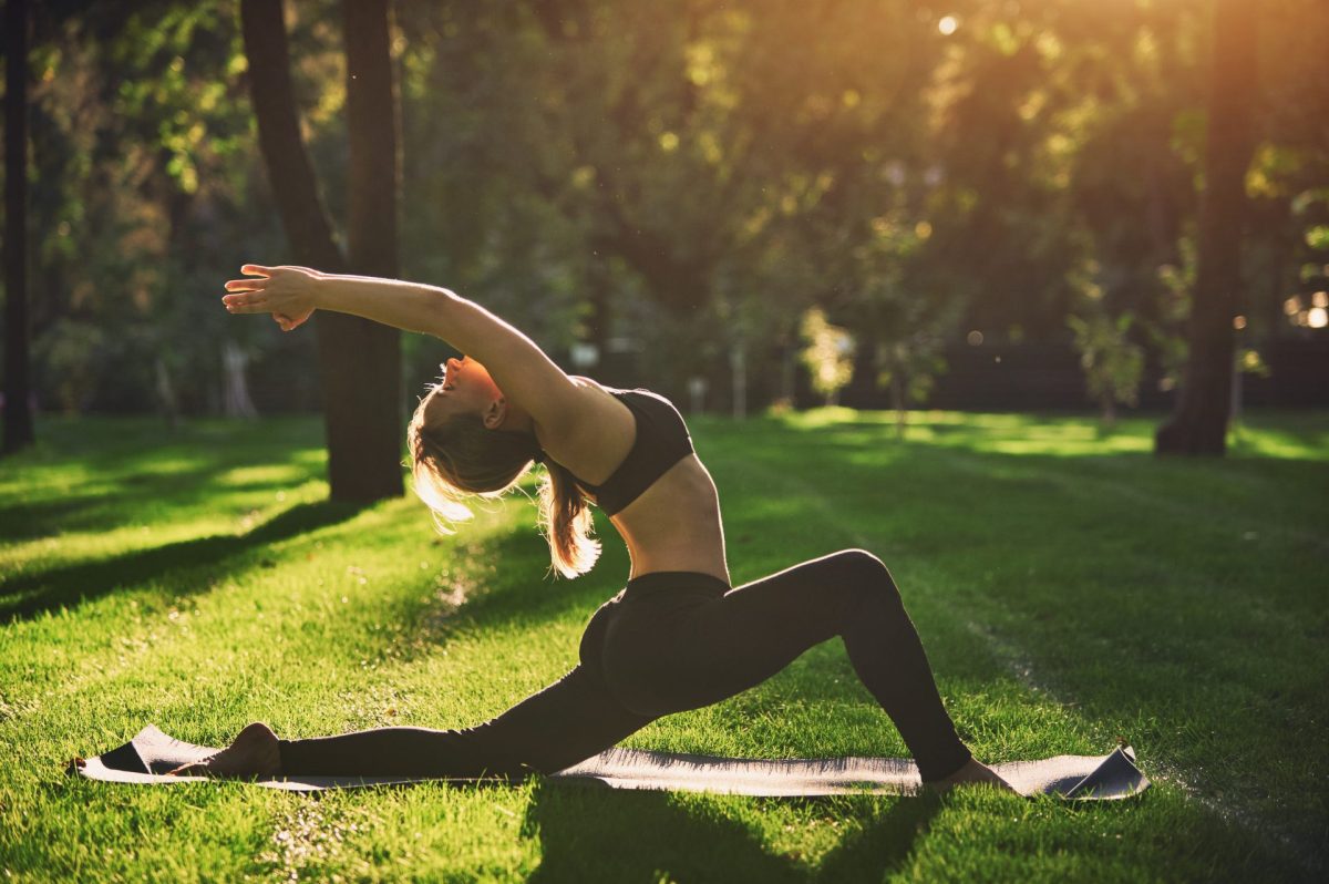 Eine Frau macht im Park Yoga.