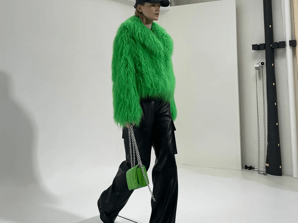 Model auf Laufband mit grünem Fake-Fur-Mantel.
