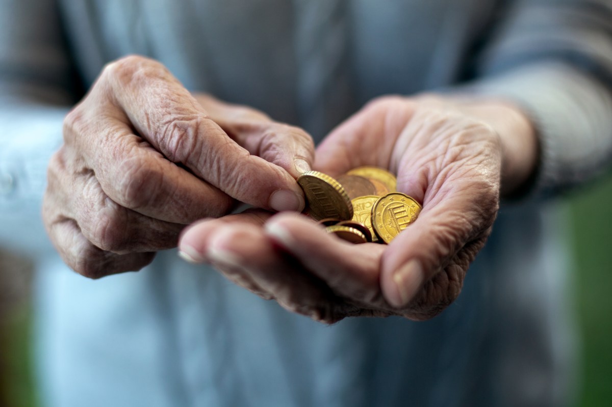 In der Hand einer alten Person liegen Münzen.