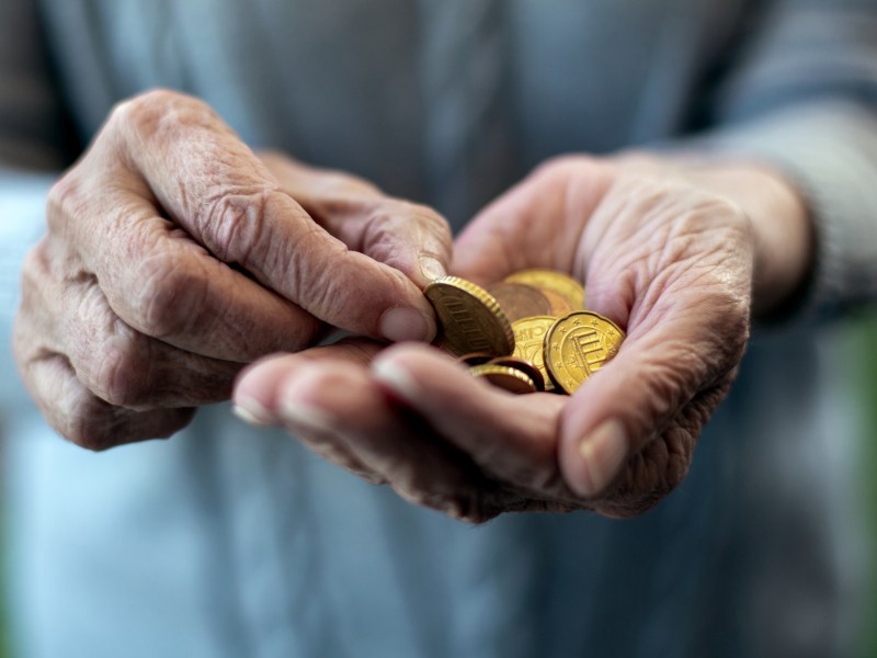 In der Hand einer alten Person liegen Münzen.