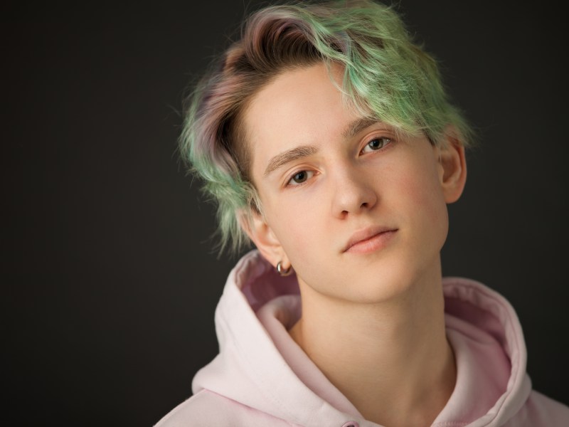 Studio-Porträt eines Teenagers mit grünen Haaren auf schwarzem Hintergrund