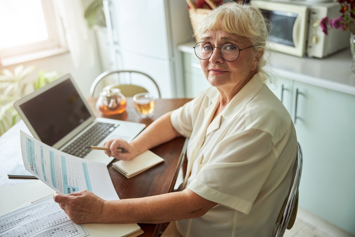 Eine Seniorin sitzt am Laptop und bearbeitet ein Steuerformular.