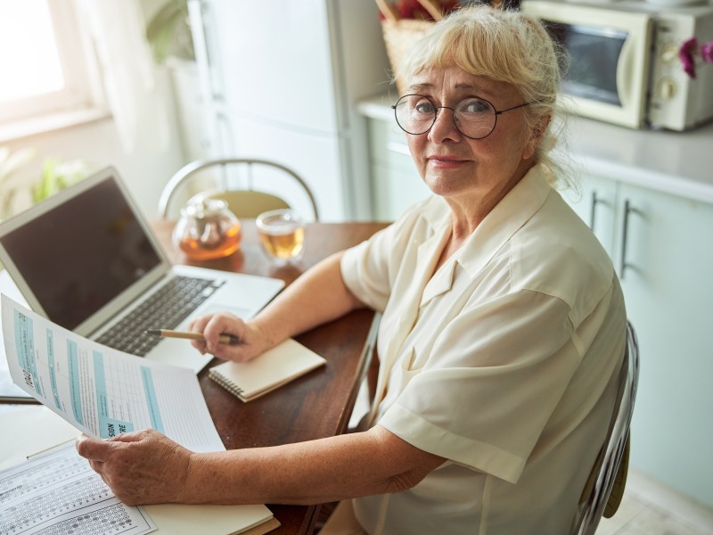 Eine Seniorin sitzt am Laptop und bearbeitet ein Steuerformular.