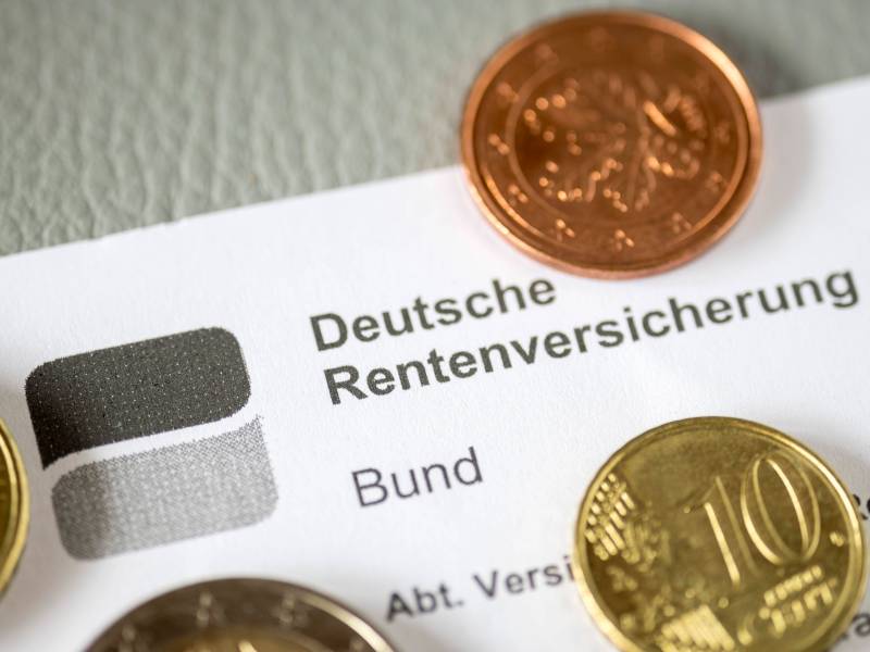 Ein Bescheid der Deutschen Rentenversicherung liegt zwischen Münzen.