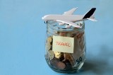 In einem Glas sind viele Münzen. Auf ihm liegt ein Flugzeug und ein Zettel mit der Aufschrift 