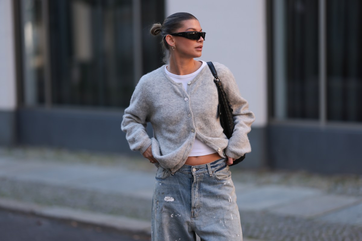 Frau mit Cardigan und Jeans geht über Straße