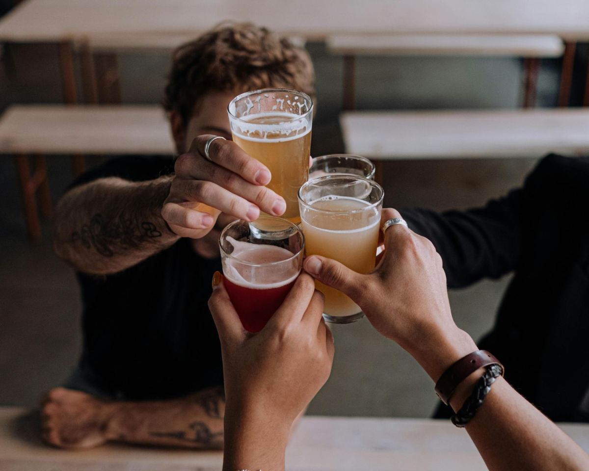 Personen stoßen mit Bier an.