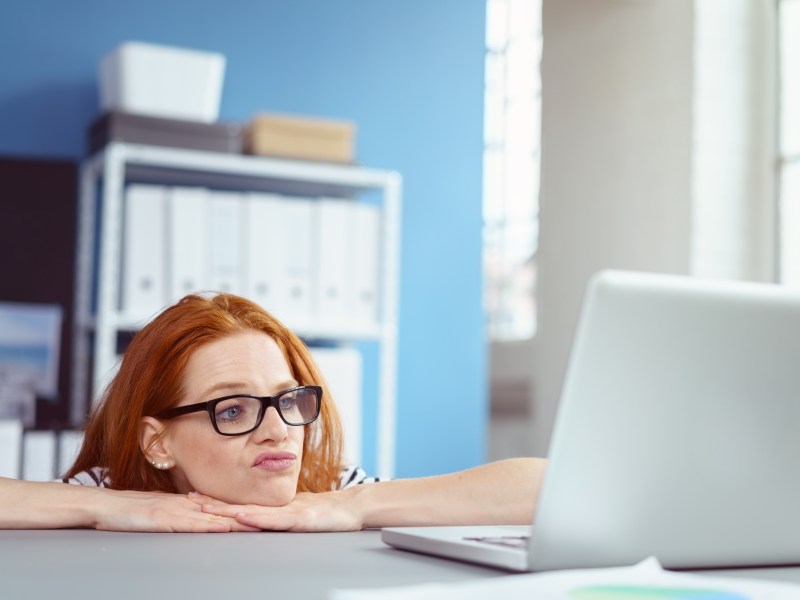 Frau mit Brille schaut genervt auf ihren Laptop.